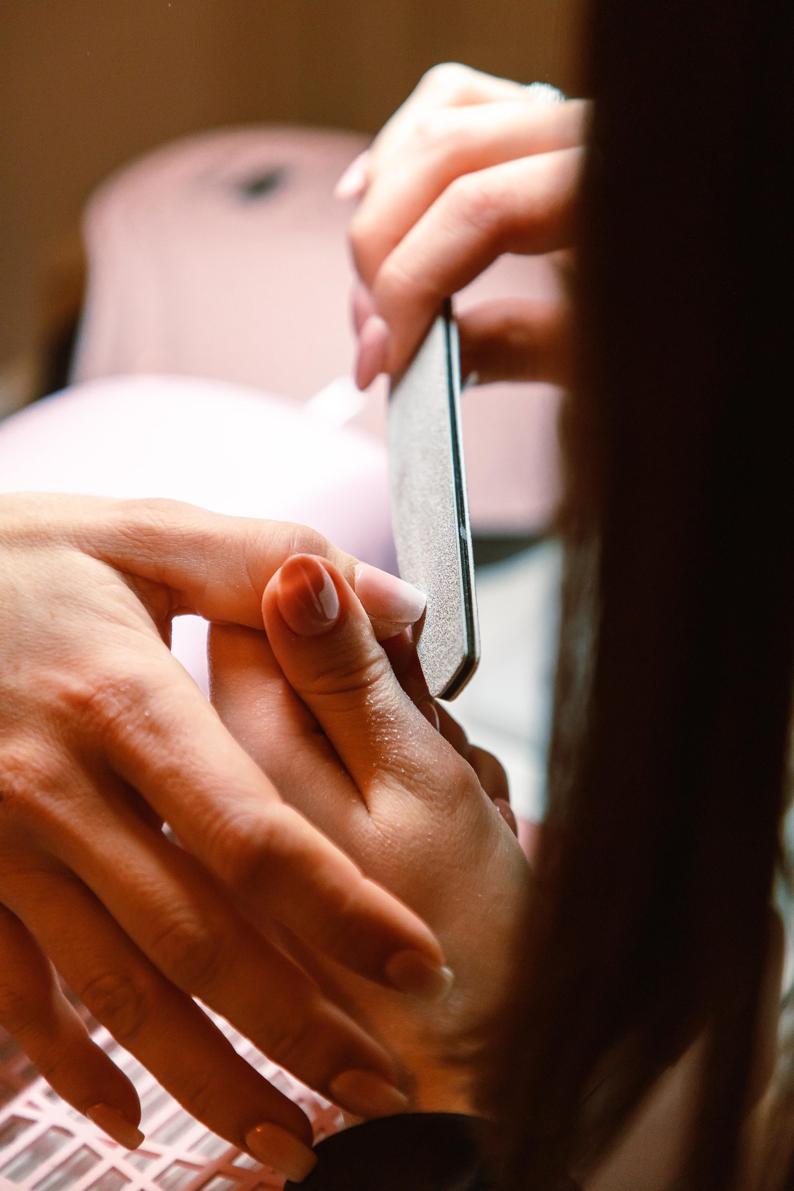 Manicurist filing a client's nails
